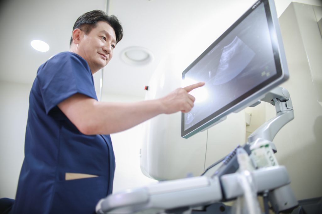 Dr. Mo Hyung-jin pointing to the ultrasound screen of the clinic's HIFU system