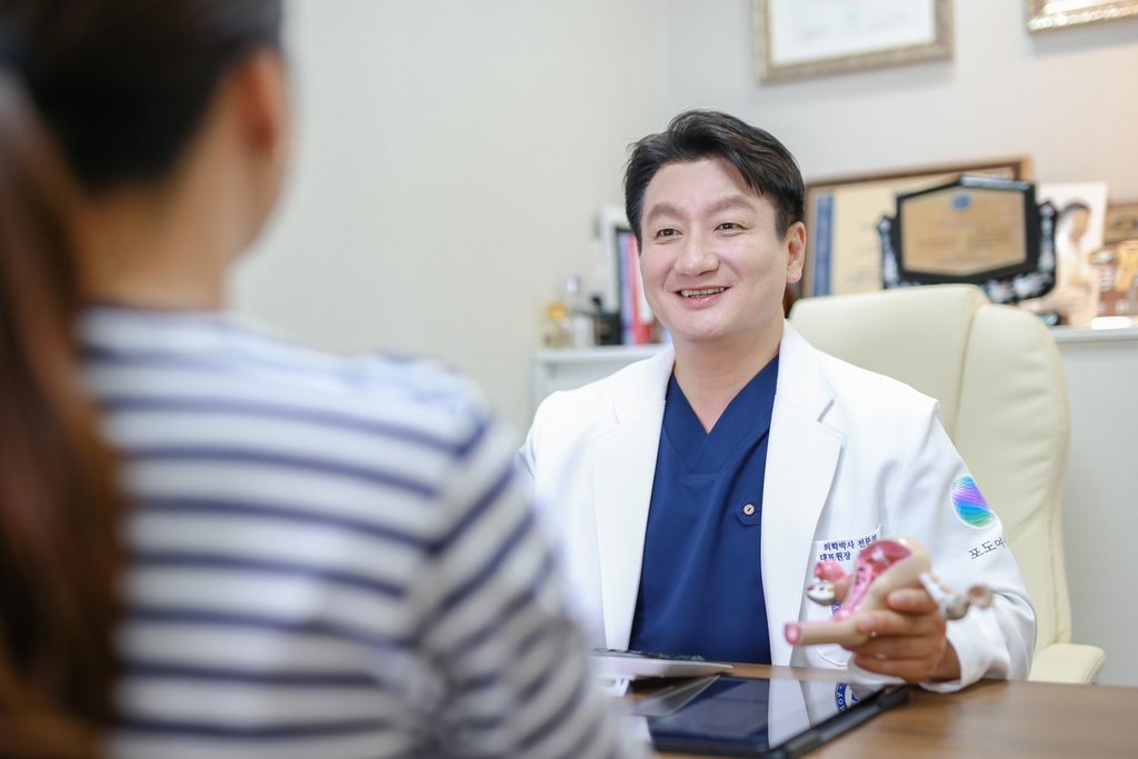 Dr. Mo Hyung-jin smiling during a consultation at his desk