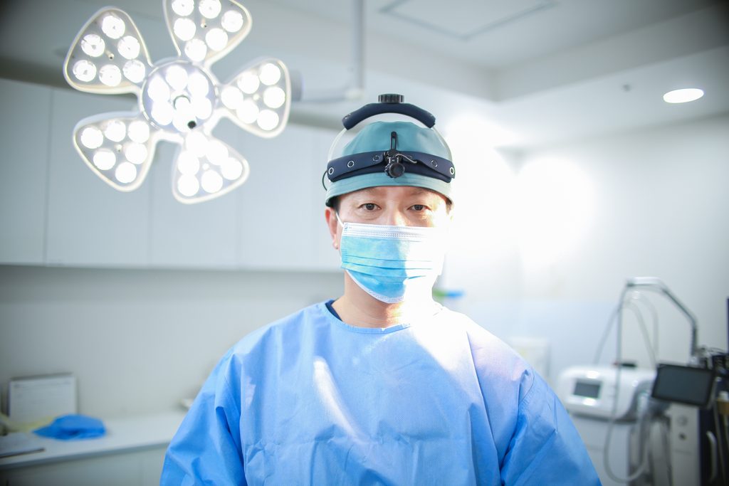 Dr. Mo Hyung-jin in a surgical gown, cap and headlight in the operating room at Gangnam Podo Woman Clinic