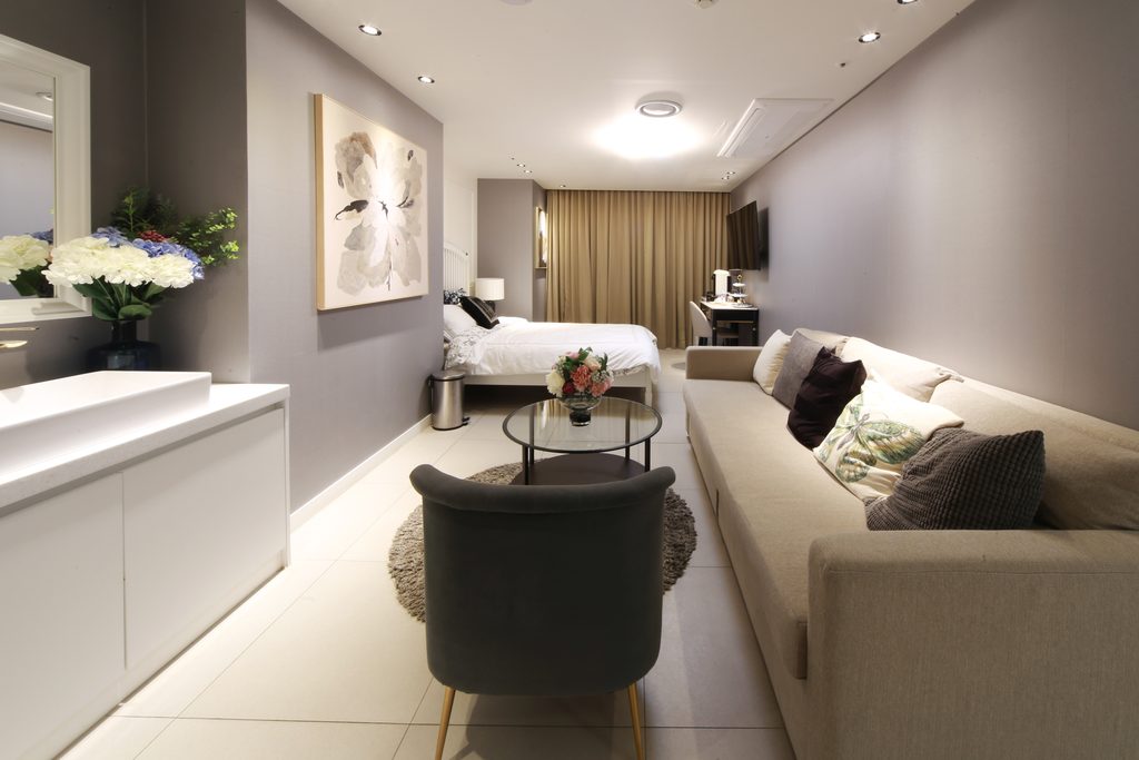 Private recovery suite at Gangnam Podo Woman Clinic with a bed, sofa and a vanity with fresh flowers